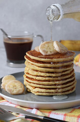 Banana cornmeal pancakes, a slide on plate, and cup of coffee