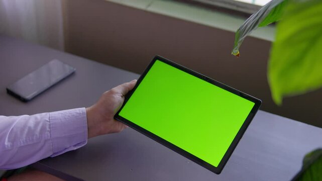 Point of view of  businessman chatting on remote working or watching online content on device. Tablet computer with green screen and chroma key for video conference. Mockup of mobile PC with greenscre