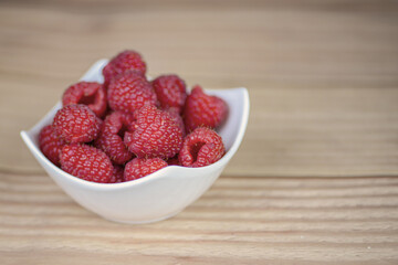 Fresh raspberries in a white plate close-up