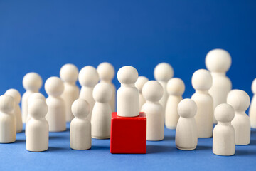 Obraz premium Competition concept. Human figure on wooden cube and other ones behind against blue background, closeup