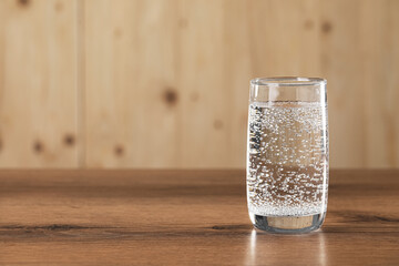 Refreshing soda water in glass on wooden table. Space for text