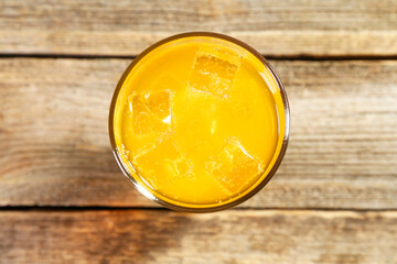 Sweet soda water with ice cubes in glass on wooden table, top view