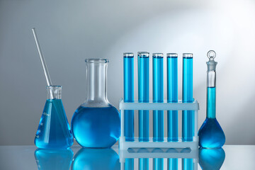 Laboratory glassware with blue liquid on mirror surface against grey background