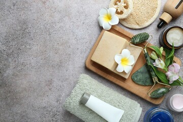 Different body care products, supplies and flowers on grey table, flat lay. Space for text