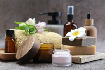 Different body care products and flowers on grey table