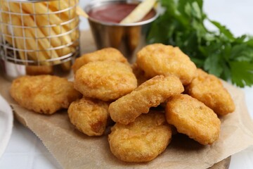 Tasty chicken nuggets, potato fries and ketchup on white tiled table, closeup