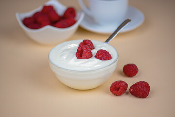 white yogurt on the table with raspberries close-up, healthy breakfast in the kitchen