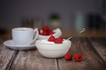white yogurt on the table with raspberries close-up, healthy breakfast in the kitchen