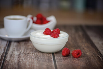 white yogurt on the table with raspberries close-up, healthy breakfast in the kitchen