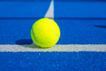 one ball on a blue paddle tennis court seen from close range