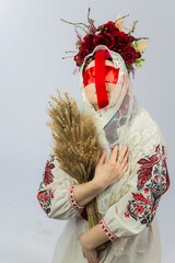 Traditional attire worn by a woman with floral crown holding dried wheat stalks in a symbolic...