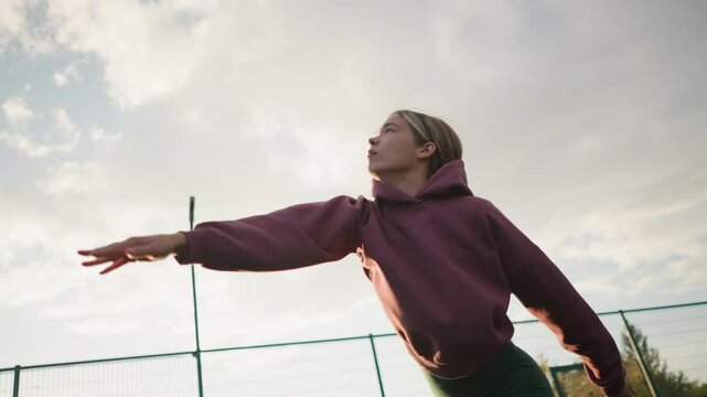 Volley ball player jumps and slams ball over net on outdoor court under sunny skies with bar net in the background, action shot of athletic woman performing sports move outdoors