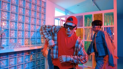 Handsome hipster wearing fancy glasses while dancing with diverse team moving along freestyle music...