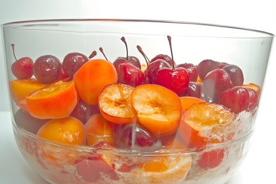 Vibrant Fruit Medley: A close-up image of a transparent glass bowl brimming with a colorful medley of fresh, ripe fruits. Capturing the essence of summer, freshness, and natural sweetness.