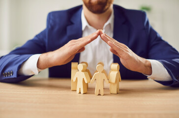 Businessman covering wooden figures of people. Employer commitment to protecting the human rights,...