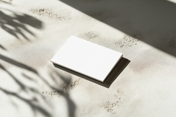 Minimalist mockup featuring a blank business card on textured concrete surface with soft shadows in a clean and ample white space environment
