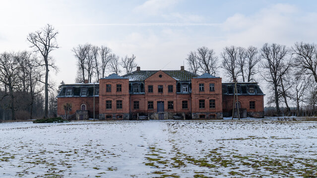 Historic Decaying Manor House Surrounded by Bare Trees. Mysterious Forgotten Estate with a Snow-Covered Foreground. 28.02.2025. katvari. Latvia.