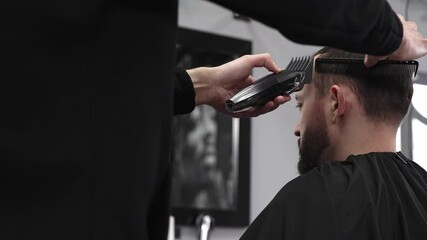 Professional barber trimming male client's hair using electric razor, creating contemporary hairstyle in sleek barbershop setting, showcasing precision grooming technique