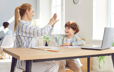 Mother is helping and assisting son with homework, and they give high five. Supportive and educational bond between a mother and son as a family, highlighting teamwork and encouragement in learning.