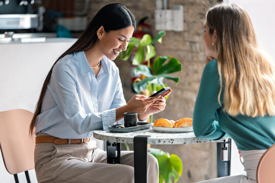 Beautiful women friends talking while having breakfast in a coffee shop