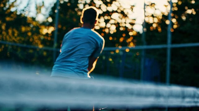 Dynamic video capturing a tennis player mid-swing, bathed in warm sunlight, emphasizing action and energy. Shot from a low camera angle.