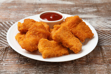 Delicious chicken nuggets with ketchup on wooden table, closeup
