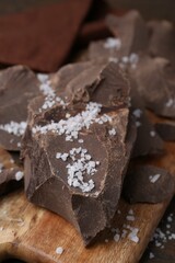 Pieces of chocolate with salt on wooden table, closeup