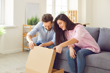 Couple looks joyfully and expectantly inside open cardboard box, looking at new purchase or gift....