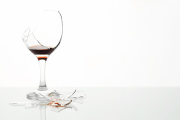 Pieces of broken glass with wine on table against white background, space for text