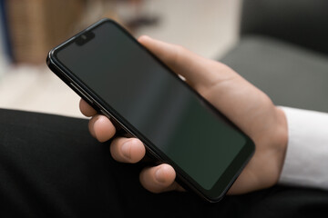 Man using smartphone with blank screen indoors, closeup