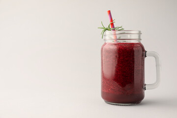 Fresh beetroot smoothie in mason jar on light grey background. Space for text