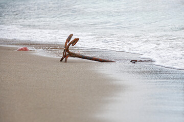 Rusted anchor for small boats on the beach