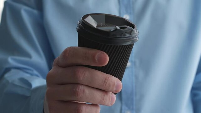 A man in a blue shirt holds a glass of drink in his hands.
A coffee glass in the hands of a man.
Black coffee glass, close-up.
A cup in the hands of a man