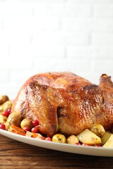 Delicious baked turkey, vegetables and cranberries on wooden table against white brick wall, space for text