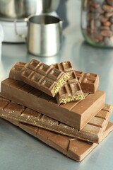 Stack of tasty Dubai chocolate bars with pistachios and knafeh on grey table