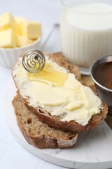 Slices of bread with butter, honey and milk on white table, closeup