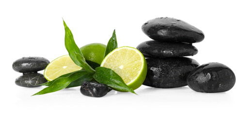 Spa composition with limes, massage stones and green leaves on mirror surface against white background