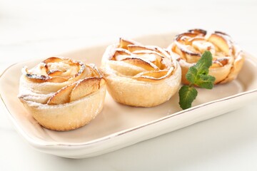 Freshly baked apple roses with mint on white table, closeup