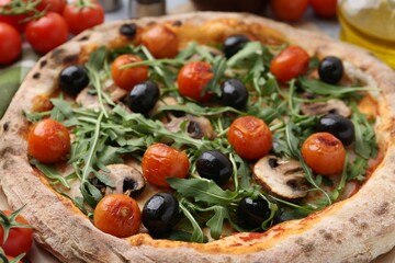 Tasty pizza with cherry tomatoes, black olives, mushrooms and arugula on table, closeup