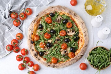 Tasty pizza with cherry tomatoes, black olives, mushrooms and arugula on white table, flat lay