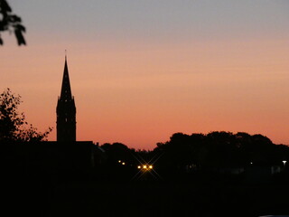 Naklejka premium Sunset in Brittany, France with an orange sky with a church in the skyline
