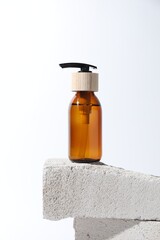 Bottle of cosmetic product on concrete block against white background