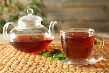 Freshly brewed tea in glass cup and teapot on wooden table