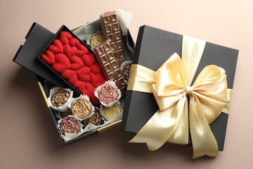Different delicious chocolate sweets in box on beige background, top view