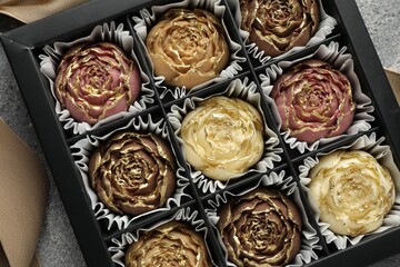 Delicious flower shaped chocolate bonbons in box on grey background, closeup