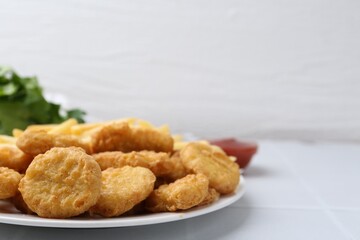 Tasty chicken nuggets and french fries on white tiled table. Space for text