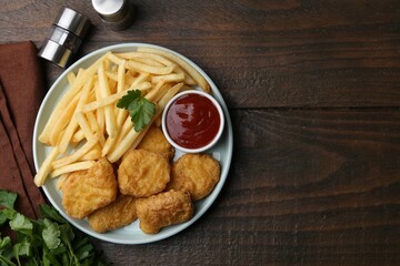 Tasty chicken nuggets and french fries with sauce on wooden table, flat lay. Space for text