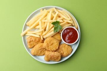 Tasty chicken nuggets and french fries with sauce on green background, top view