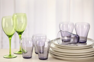 Empty clean glasses and plates on wooden table indoors