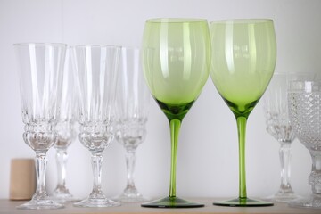 Empty clean glasses on shelf near white wall indoors